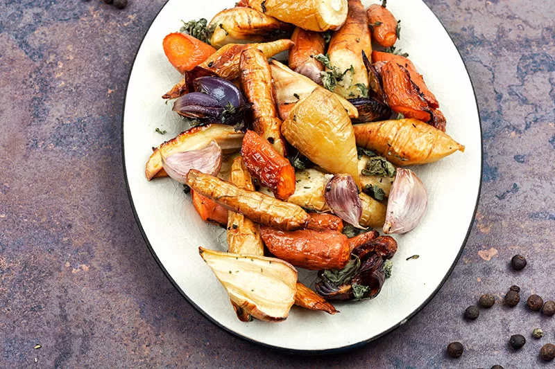 A plate of roast vegetables, including roast garlic