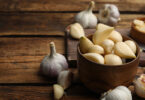 Whole garlic and garlic gloves on a wooden table