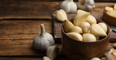 Whole garlic and garlic gloves on a wooden table